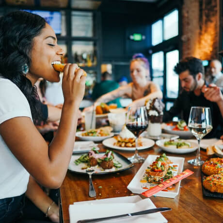 Grupo de amigos disfrutando de una comida italiana en un restaurante, con platos tradicionales y copas de vino sobre la mesa, representando la gastronom&iacute;a italiana en Roma, 2025.
